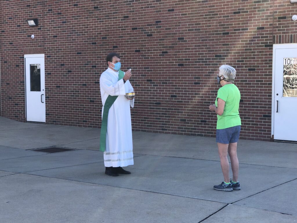Deacon Paul offers communion outside the church during the pandemic