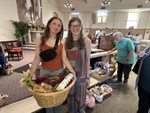 Two young women hold a basket of foods blessed for Easter